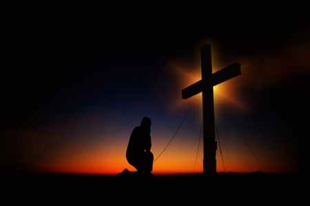 man kneeling in front of cross